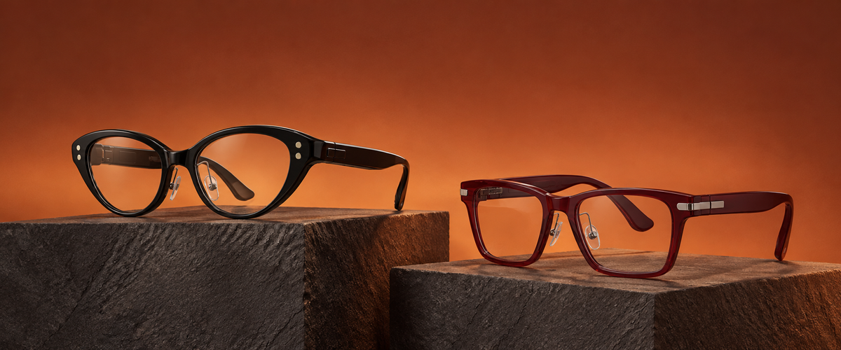 Hearview Lite black Cat-eye and red Classic glasses on stone blocks against a copper background